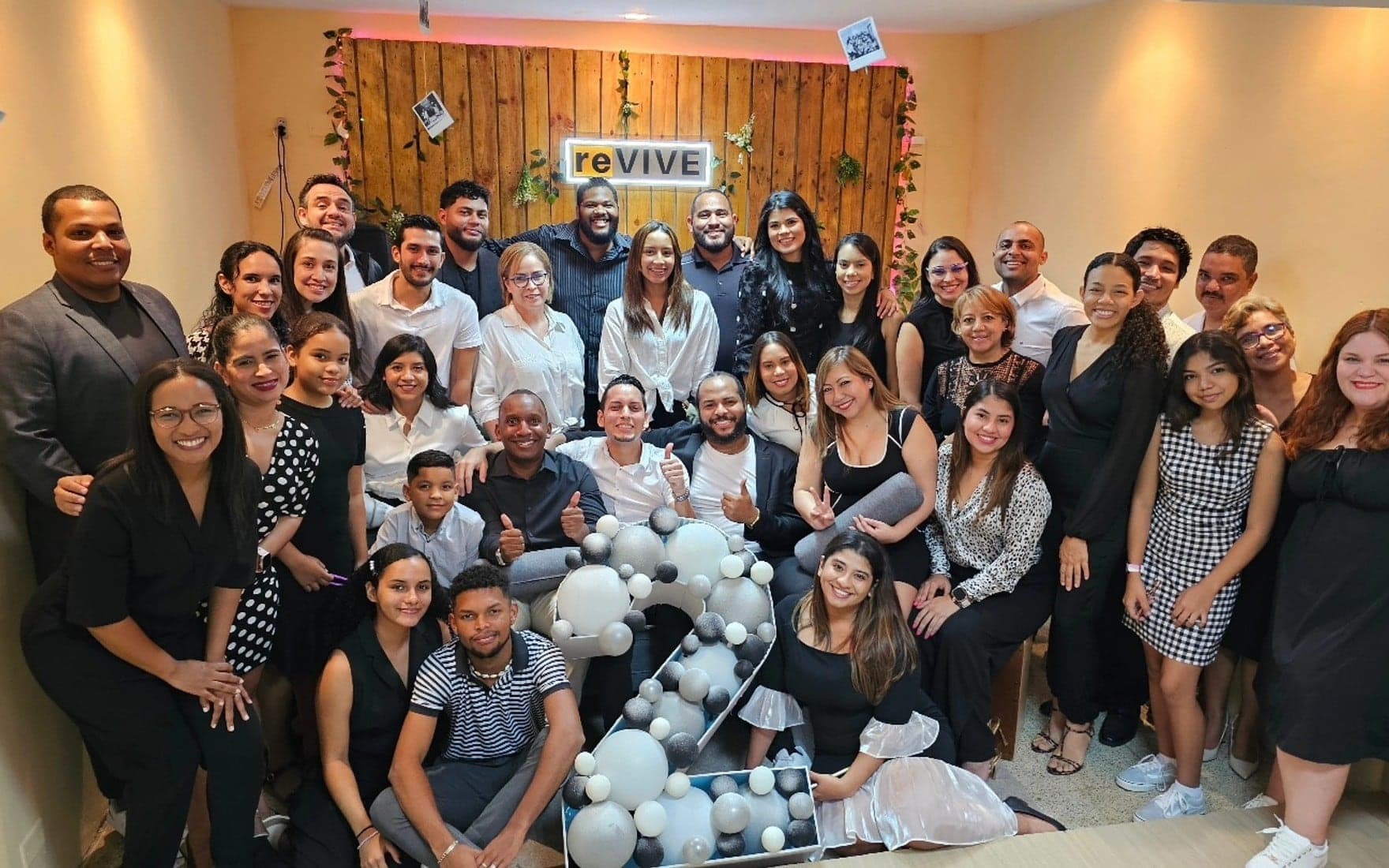 La iglesia completa celebrando otro año de reVIVE frente a la pared de madera con el letrero
